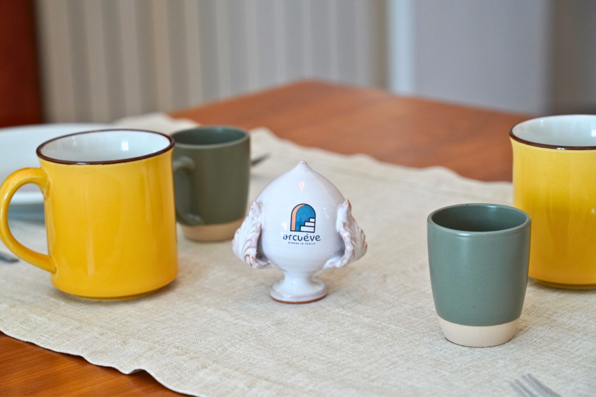 A table with four mugs and a decorative item.