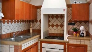 A kitchen with wooden cabinets, a tiled backsplash, a stove, and a sink. - Dimora GiuLè - Arcuève (Ostuni)
