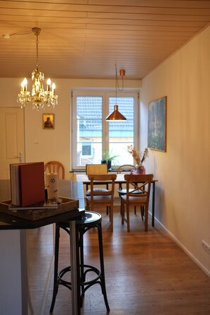 A dining area with wooden flooring, a chandelier, and a table with chairs.