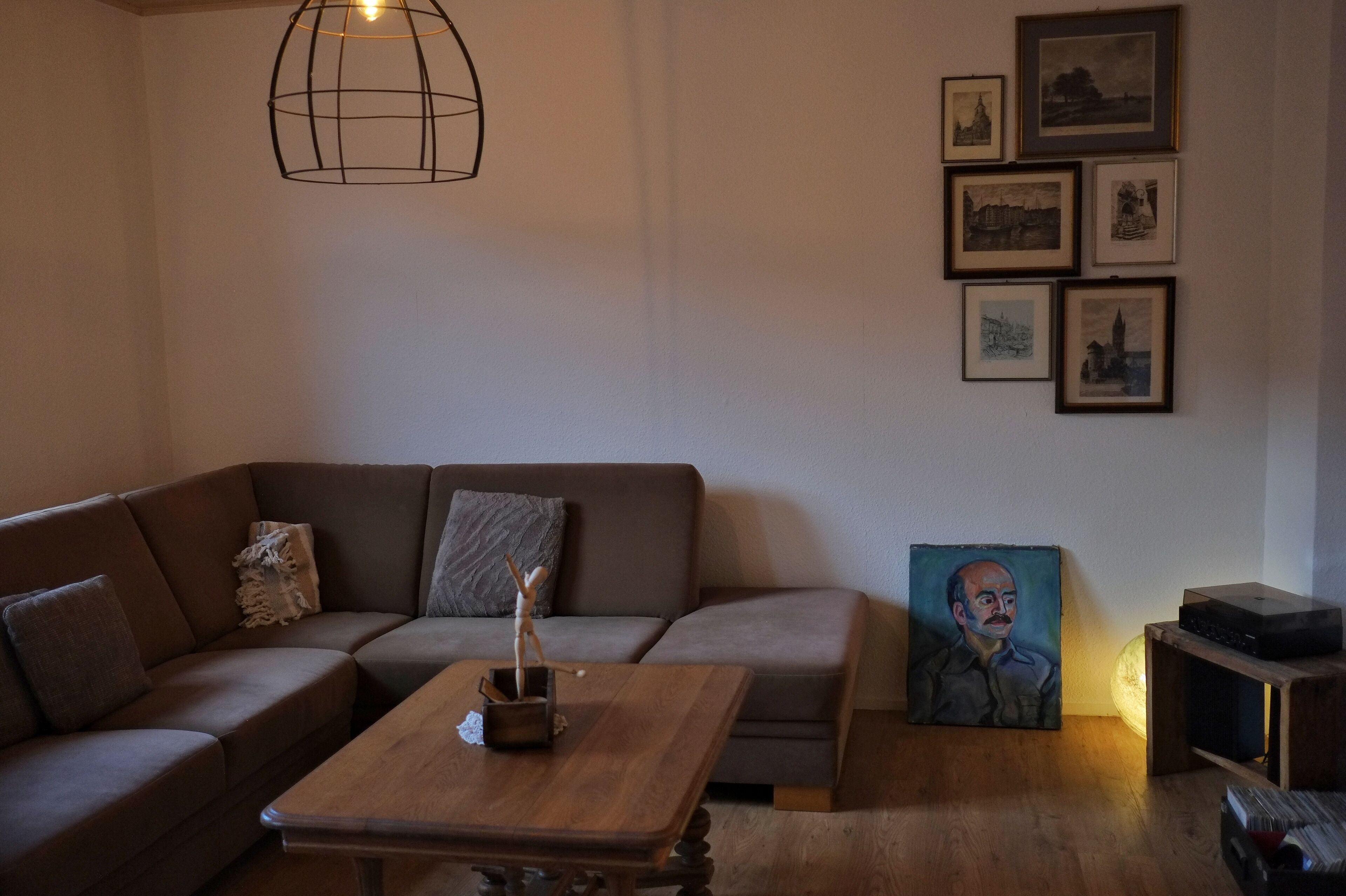 Un salon avec un canapé marron, une table basse en bois et un tableau encadré.