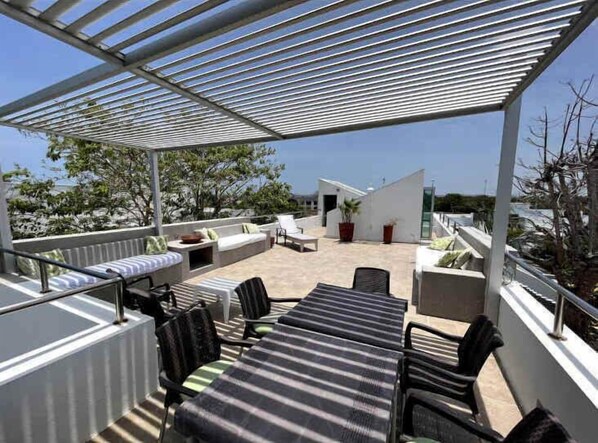 A rooftop terrace with a pergola, outdoor seating, and a view of the surrounding landscape. - NOK Luxury 4BR Pool Villa in Manzanillo Cartagena (Cartagena)