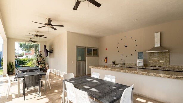 A spacious patio with a dining table and chairs, a kitchen area with a granite countertop, and ceiling fans. - Casa Nido de Mar 9 Persons Occupancy Pool 7 Beds (Nuevo Nayarit)