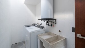 A laundry area with a washing machine, a concrete sink, and a water heater mounted on the wall. - Casa Nido de Mar 9 Persons Occupancy Pool 7 Beds (Nuevo Nayarit)