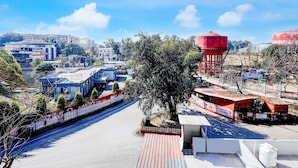 A street view with buildings, a water tower, and a tree. - Classic Survey Chowk Dehradun (Dehradun)