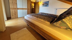 Quarto com estrutura de cama de madeira, uma janela grande e um guarda-roupa de madeira.