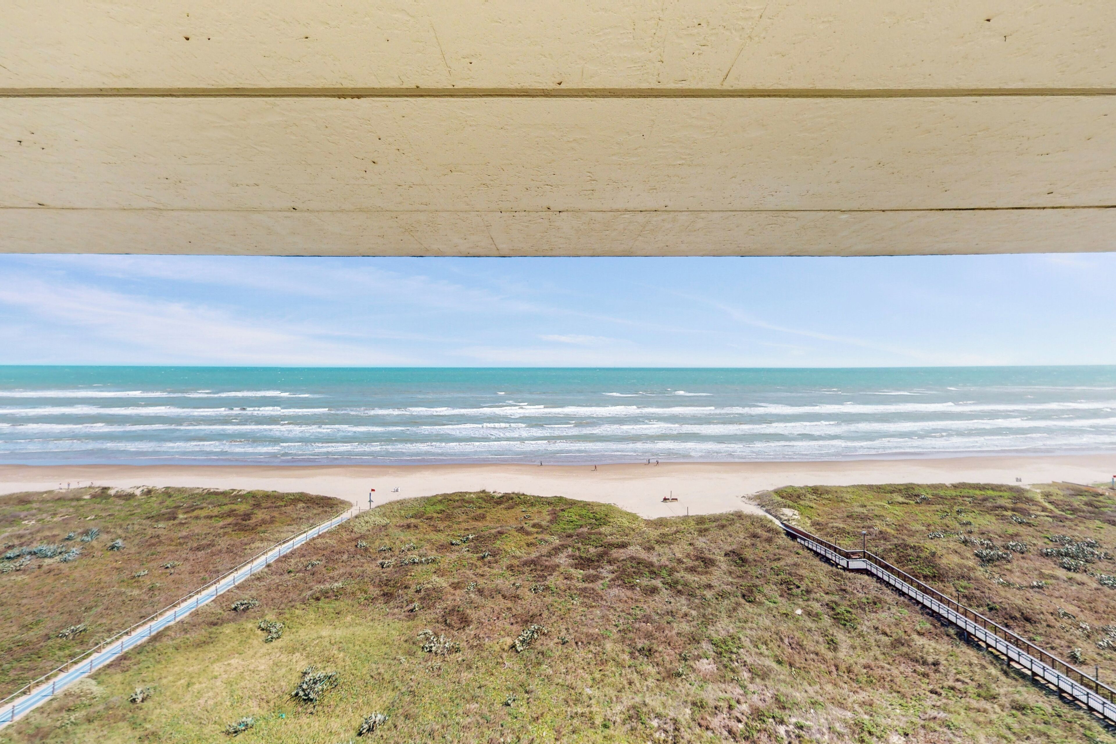 Blick auf einen Strand mit einer Holzpromenade, die zum Ufer führt.