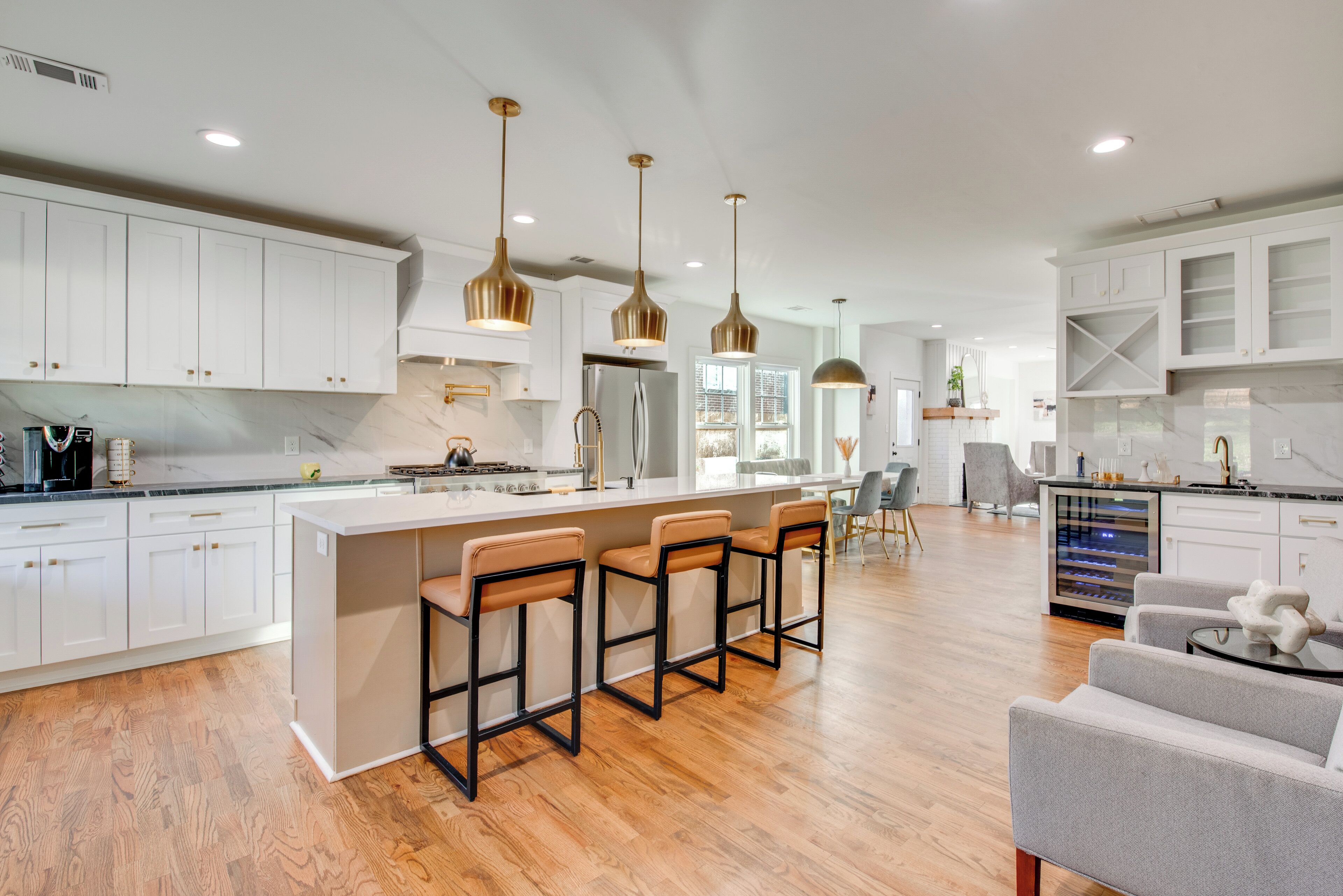 A modern kitchen with white cabinets, a central island with bar stools, and pendant lighting.