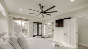A bedroom with a large bed, a ceiling fan, and a view of the outside. - Home Theater + Rooftop Deck! Fountain Sq Stunner (Indianapolis)