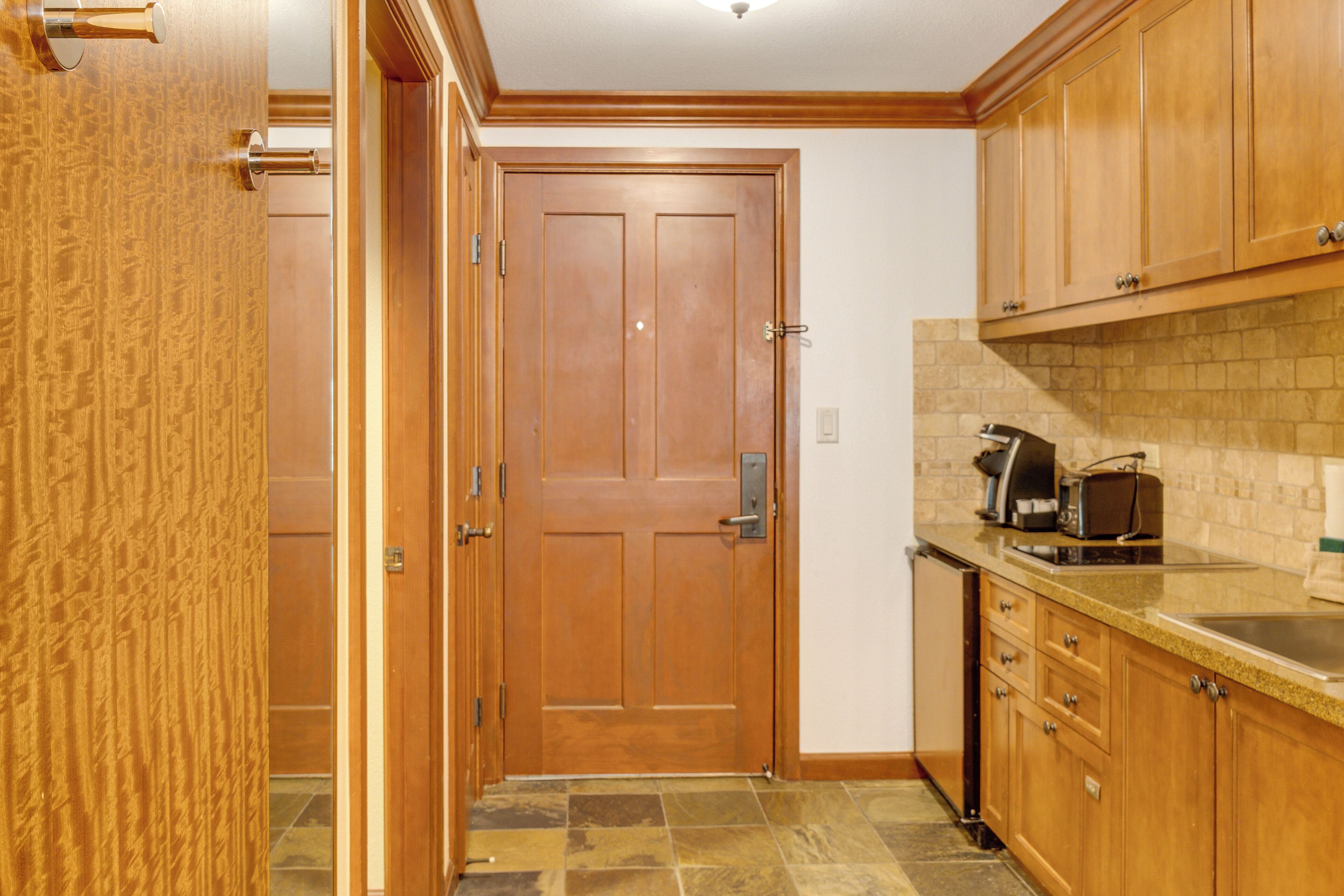 A kitchen with wooden cabinets, a tiled backsplash, and a coffee maker on the counter.