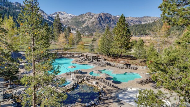 Un resort con diverse piscine, una vasca idromassaggio e montagne sullo sfondo.