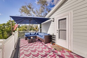 Eine Terrasse im Freien mit einer Couch, einem großen Sonnenschirm und einem gemusterten Teppich.