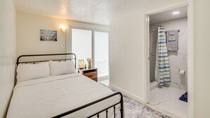 Ein Schlafzimmer mit einem Bett, einem Nachttisch, einem Gemälde und einem durchgegangenen Tür erkennbaren Badezimmer.