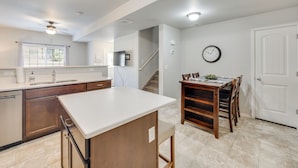 A modern kitchen with a central island, wooden cabinets, and a dining area with a wooden table and chairs. - Nurse-friendly Rental 2 Mi to St Francis Hospital! (Colorado Springs)
