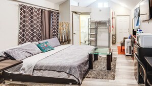 A modern bedroom with a bed, a glass coffee table, and a TV. - 8 Mi to Dtwn Cle: Cozy Couple's Retreat w/ Gym! (Cleveland)