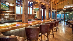 Eine Bar mit Holzbalken, einer langen Theke und ledernen Barhocker.