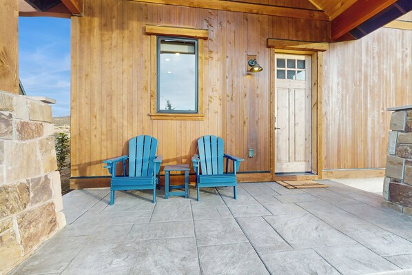 A wooden exterior with two blue Adirondack chairs and a small table on a stone patio. - Golf Access On-site! Home w/ Shared Pool (Powell Butte)