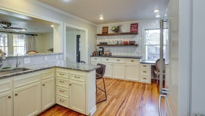 A kitchen with white cabinetry, granite countertops, and a herringbone-patterned backsplash. - 1 Mi to Texas Tech: Group Getaway w/ Pool & Sauna! (Lubbock)