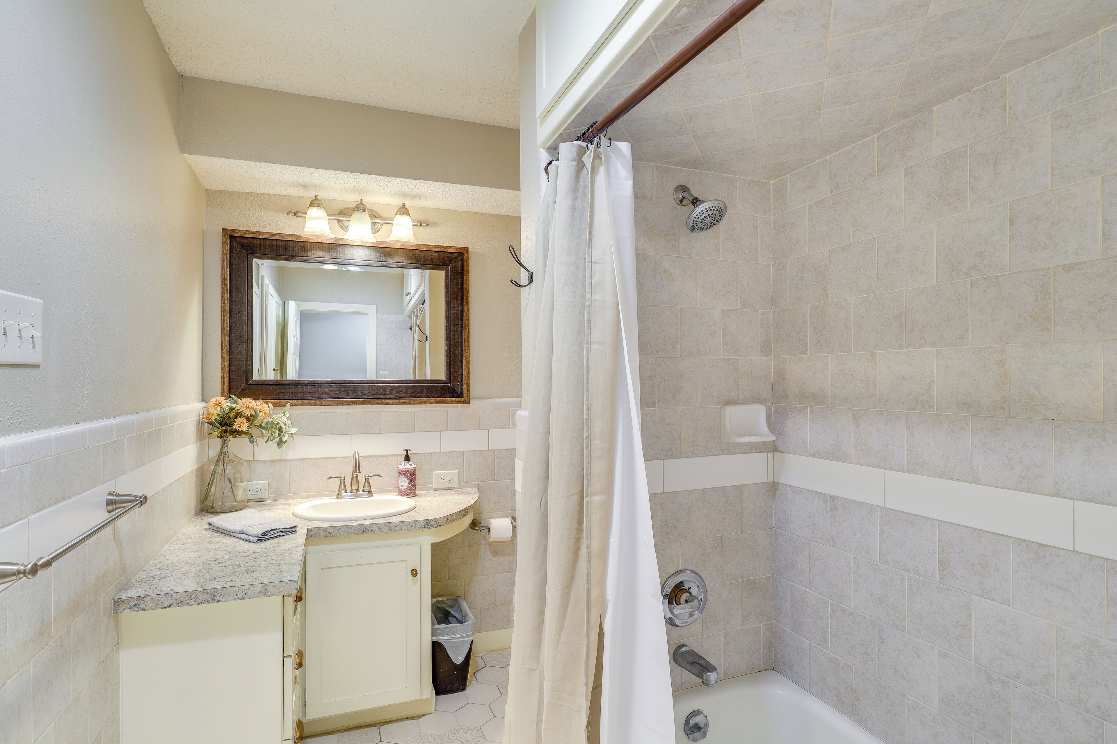 Un baño con ducha, lavabo y espejo.