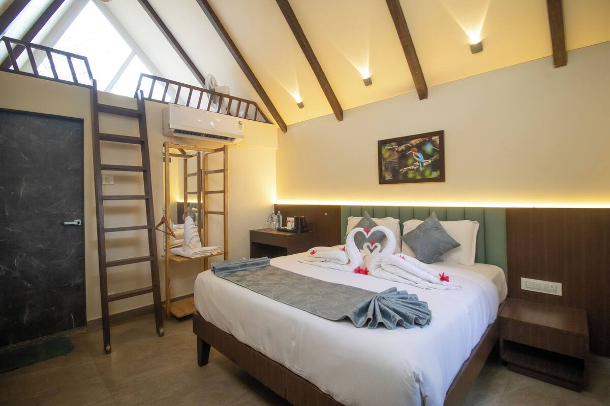 Ein Hotelzimmer mit Schlafkoje, einer Leiter, einer Klimaanlage, einem Nachttisch, einer Wanddekoration und einem Bett mit Handtüchern und Decke.