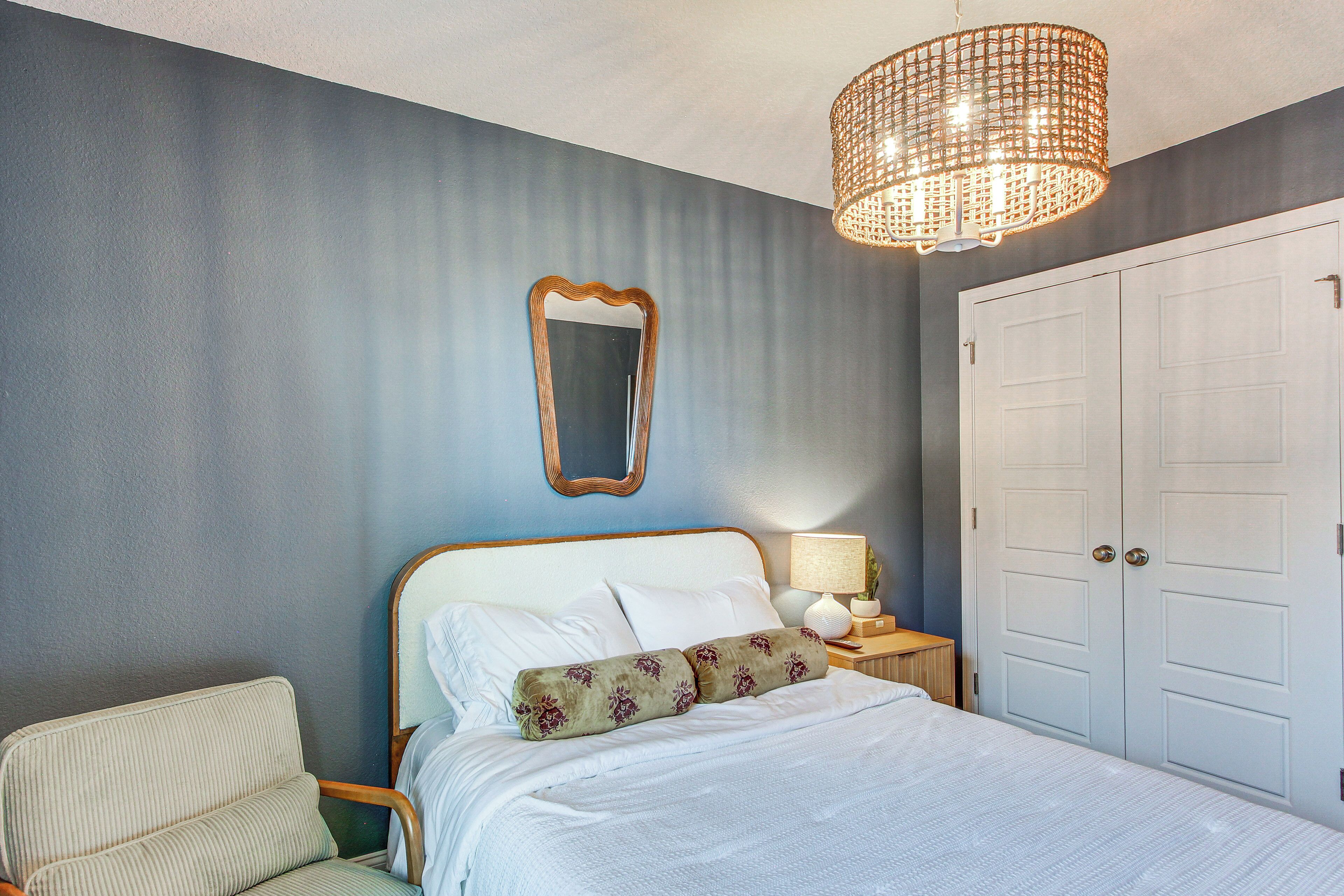 Ein Schlafzimmer mit Bett, Stuhl, Spiegel, Lampe und Kleiderschrank.