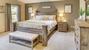 Une chambre à coucher avec un lit en bois, des tables de chevet, un banc et une commode.