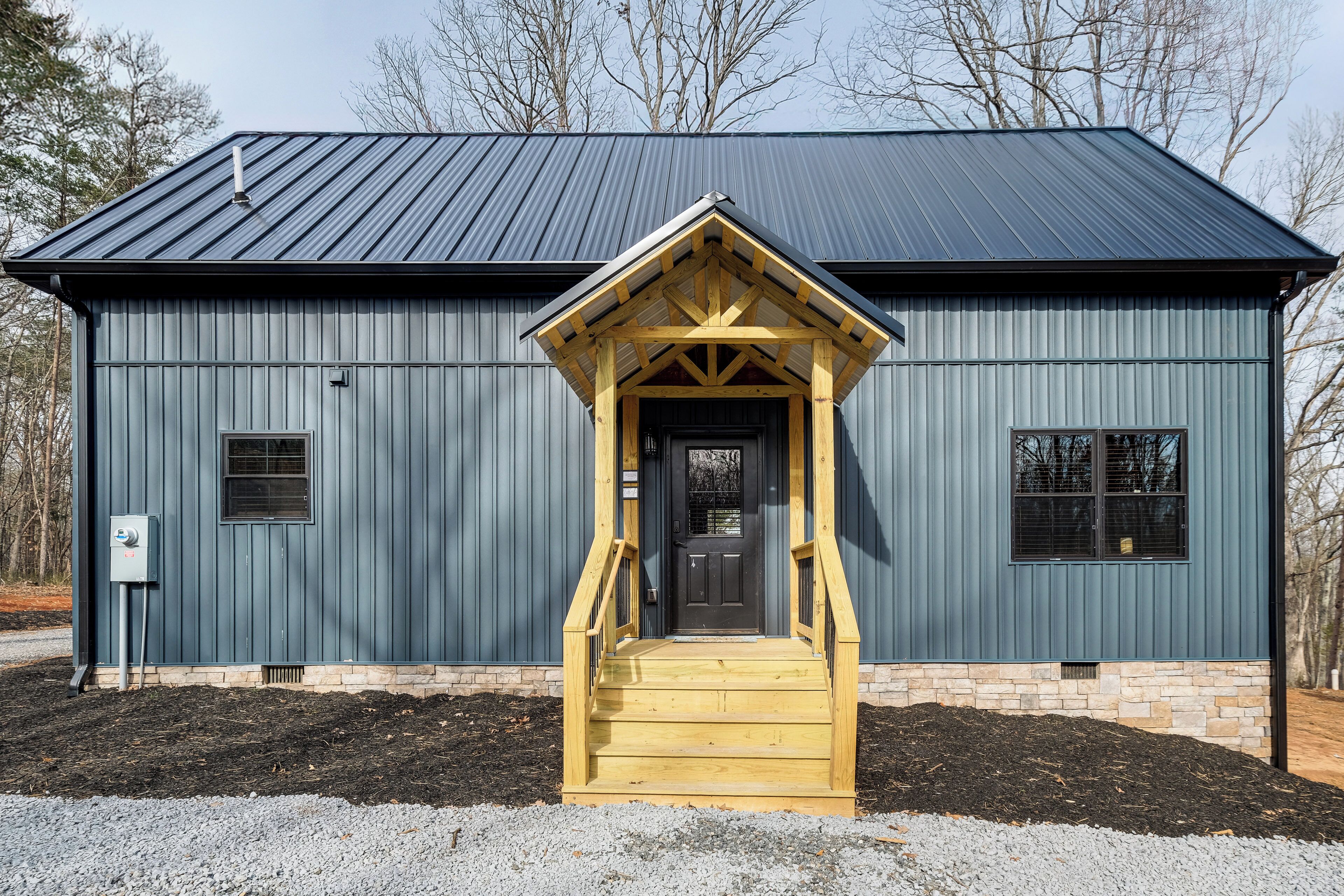 A building with a dark blue exterior, a wooden front porch, and a black door.
