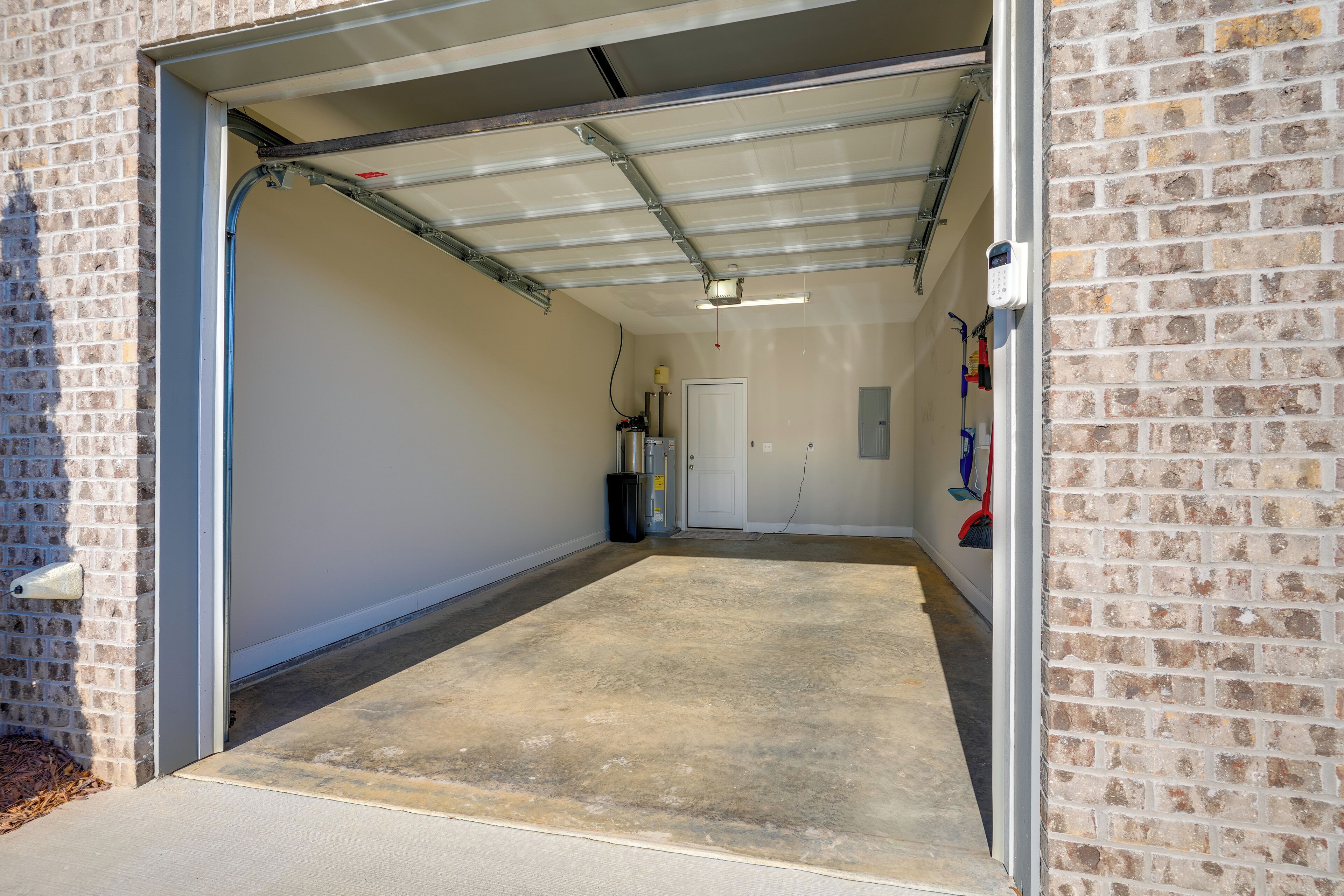 Un garage avec un sol en béton, une porte métallique et un mur en briques.