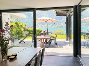 An outdoor dining area with a table, chairs, and a view of a lake and mountains. - Villa am See 5 / Beach House by Interhome (Sisikon)