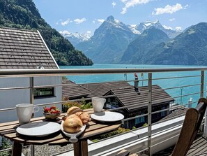 A balcony with a table set for breakfast, overlooking a lake and mountains. - Villa am See 5 / Beach House by Interhome (Sisikon)