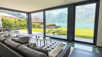 A modern living room with a large window overlooking a lake and mountains.
