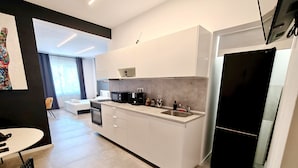 Una cocina moderna con armarios blancos, un refrigerador negro y una zona de comedor con una mesa y sillas.