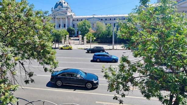 Un estacionamiento con varios coches y un edificio grande con una cúpula al fondo.