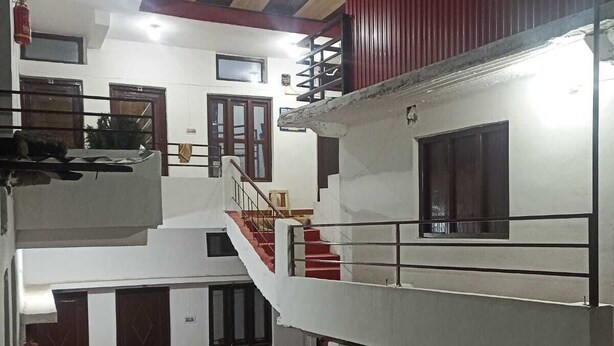 A multi-story residential building with a staircase connecting the floors, a balcony on the upper level, and a small garden area with potted plants. - Hotel Geeta Palace (Ukhimath)
