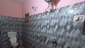A bathroom with a toilet, bidet, sink, and a water heater mounted on the wall. - Hotel Geeta Palace (Ukhimath)