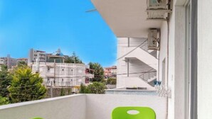A balcony with a green table and chairs, overlooking a cityscape. - Central Garden Sofia Studios (Ksamil)