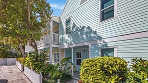 A two-story house with a porch, white picket fence, and various shrubs. - A & E's Tranquil Tides at the Truman Annex in Key West (Key West)