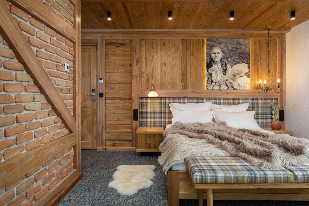 A cozy bedroom with a wooden headboard, a plaid bedspread, and a fluffy rug.