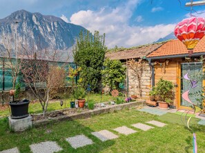 Una casa con fachada de piedra, puerta de madera y jardín con plantas en macetas y un globo aerostático.