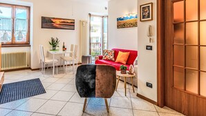 Un salon moderne avec un canapé rouge, un fauteuil noir et marron, une table à manger et un ventilateur de plafond.