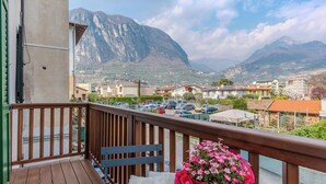 Un balcon avec une balustrade en bois, une table, une chaise et un pot de fleurs contenant des fleurs roses.