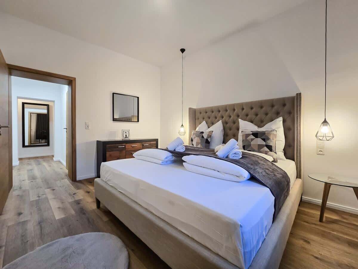 A bedroom with a large bed, bedside tables, a wardrobe, and a mirror.