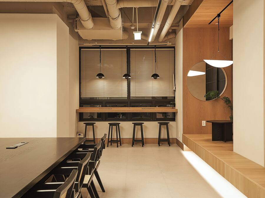 A modern kitchen with a long counter, stools, and pendant lighting.