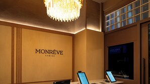 A Monréve hotel reception desk with a chandelier, a digital screen, and a window with blinds. - Monrêve Cabins Seoul Gangnam (Seoul)