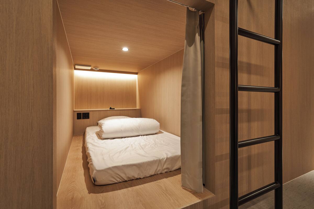 A modern bedroom with a wooden ceiling, a bed with white bedding, and a black metal ladder.