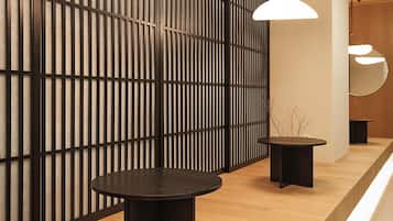 Un intérieur moderne avec un comptoir d’accueil en bois, des suspensions noires et une cloison en lattes de bois.