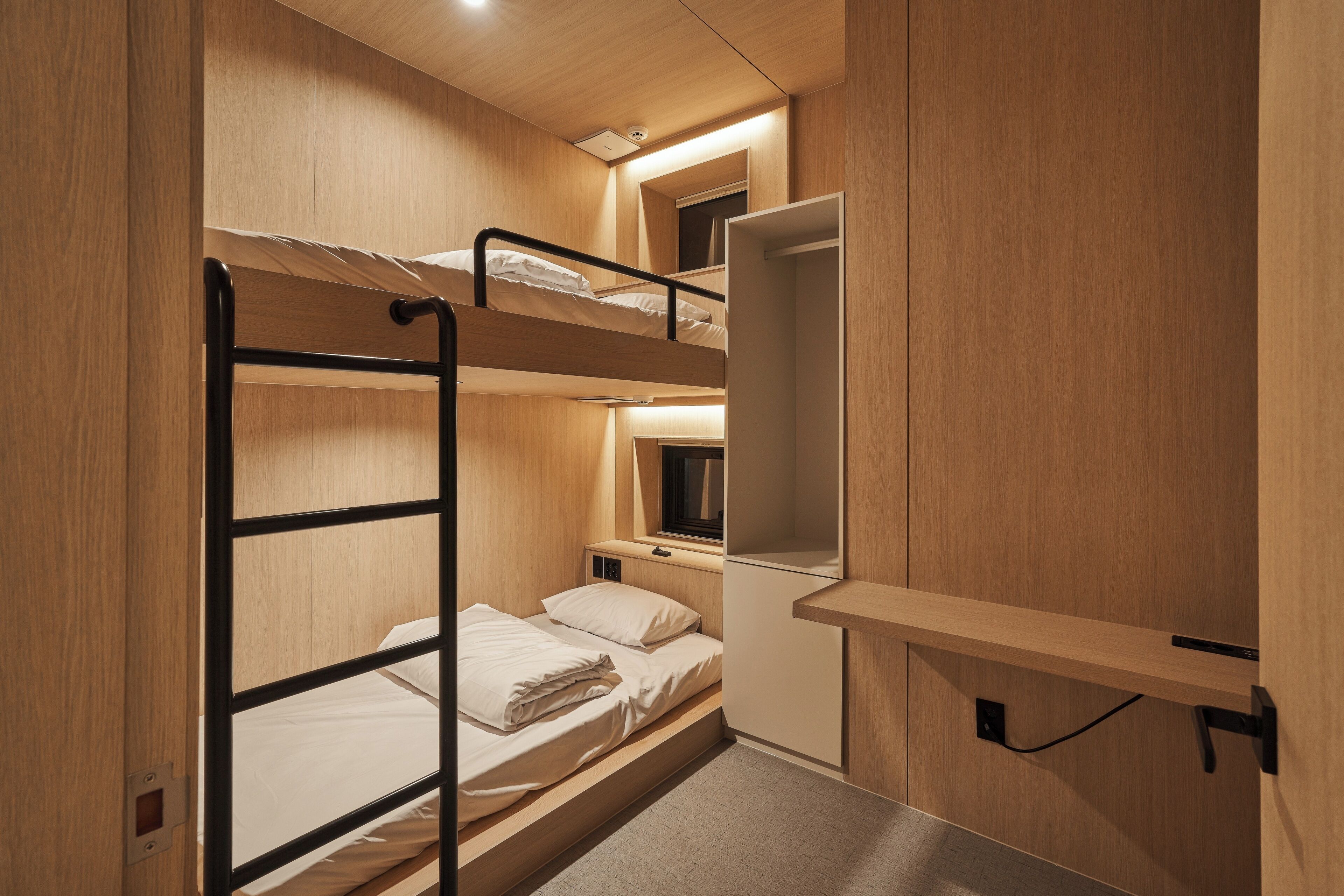 A bunk bed room with a desk and a mirror.