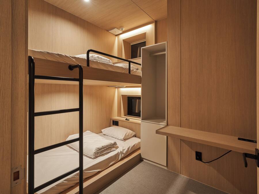 A bunk bed room with a desk and a mirror.