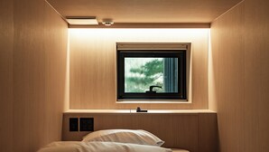 A compact bedroom with a built-in window, a bedside control panel, and a bed with white bedding. - Monrêve Cabins Seoul Gangnam (Seoul)