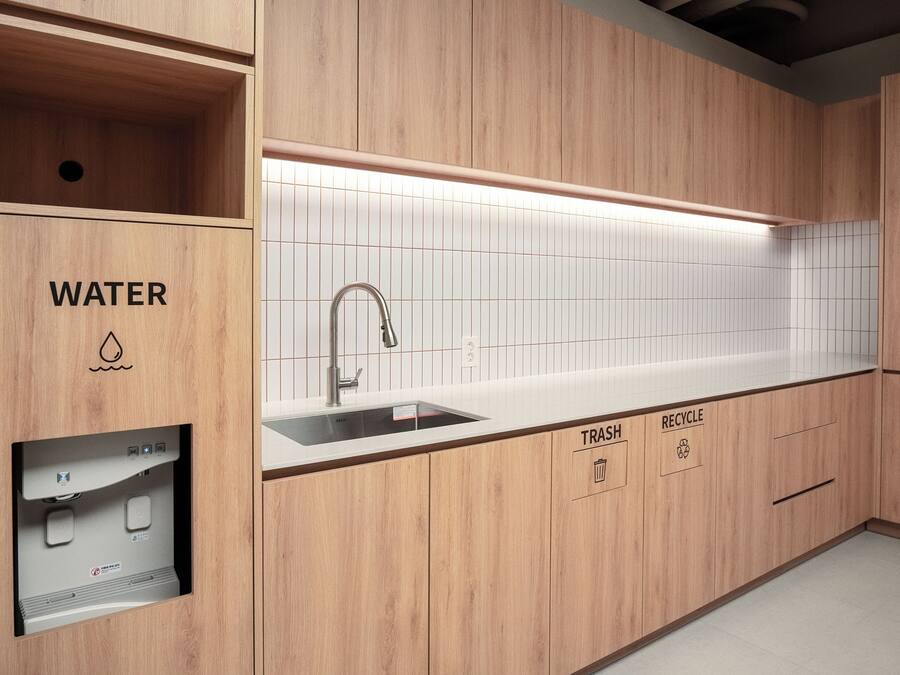 A modern kitchen with wooden cabinetry, a built-in sink, and a water dispenser.
