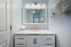 A bathroom with a marble sink, a large mirror, and a towel rack. - Sea Bright Gem Steps To Beach + Parking 4 Bedroom Home (Rumson)